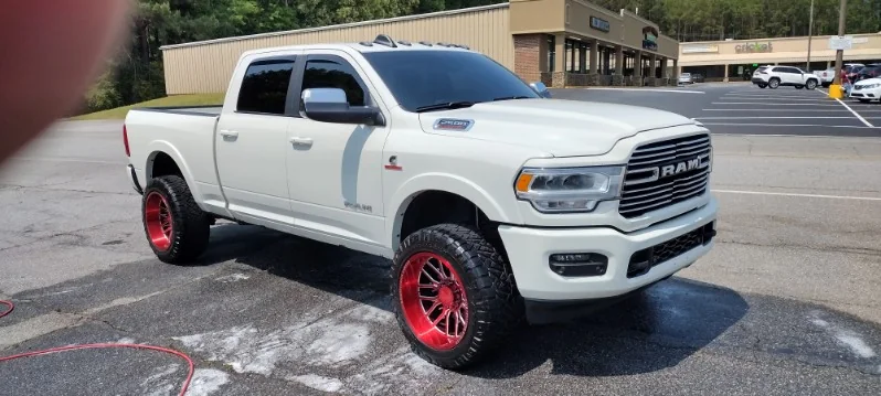 Lifted white Ram 2500 Laramie on red wheels cleaned up by Grindtime